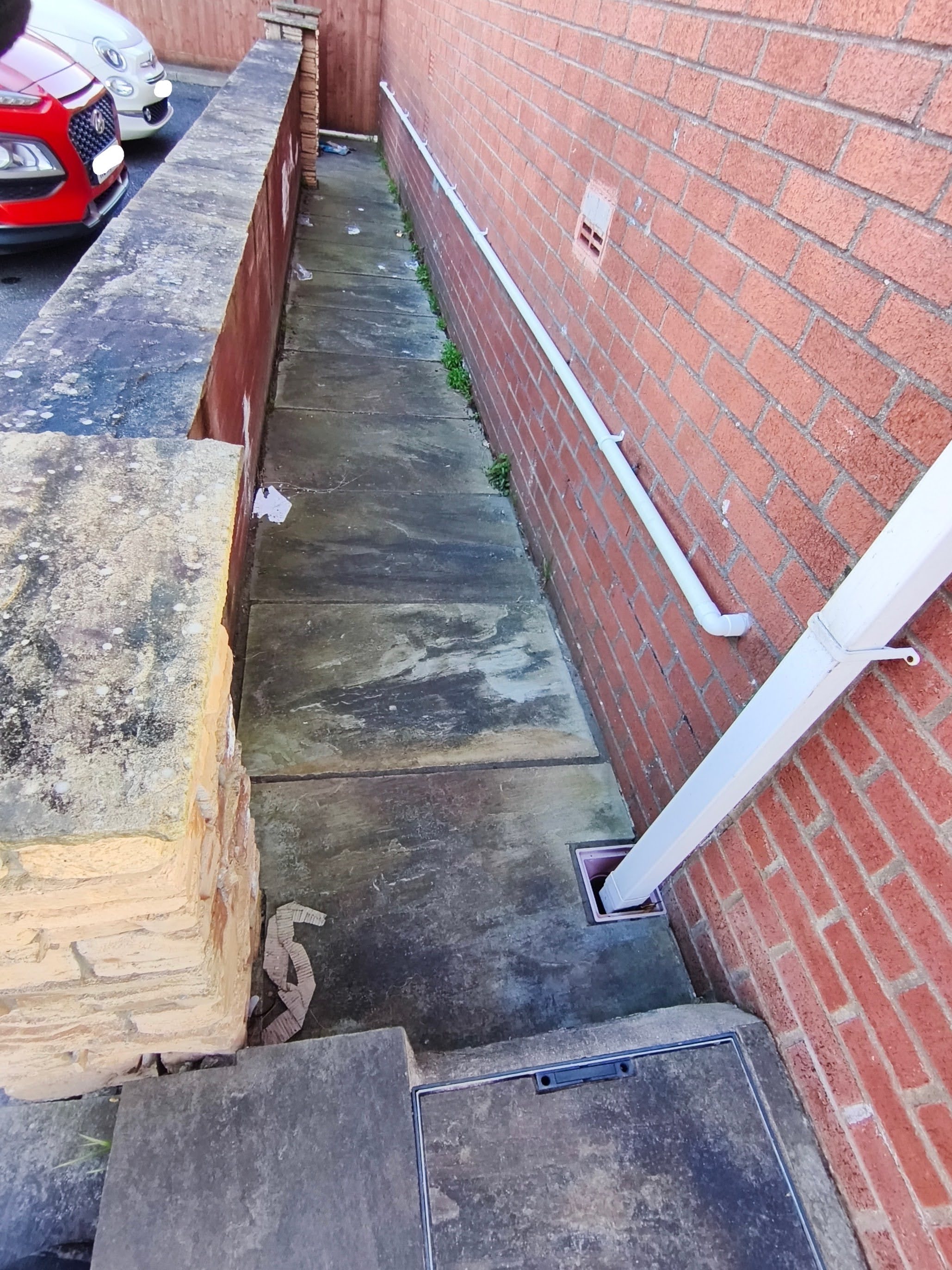 Before sidepath cleaning: weathered paving with organic growth and staining